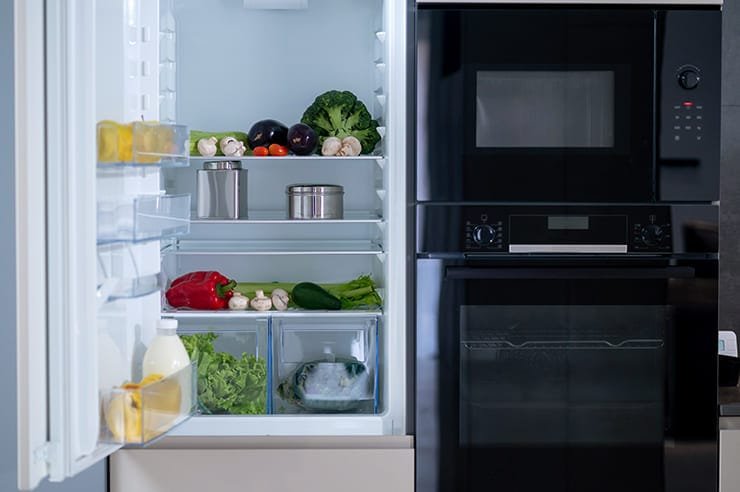 A white refrigerator filled with various vegetables.