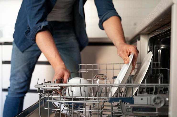 Man Reaching for clean dishes in the dishwasher