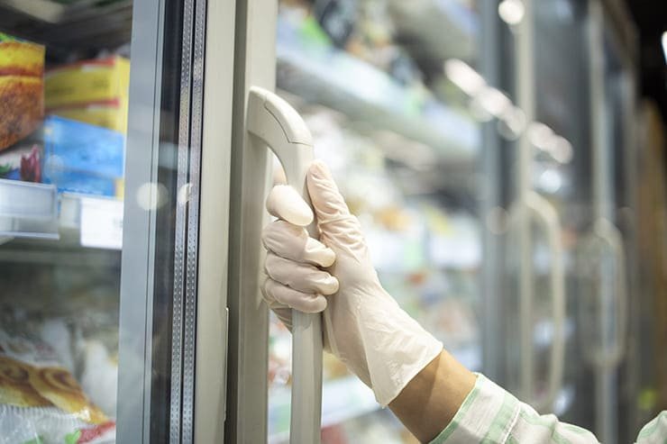 A person wearing gloves reaching for food in the fridge
